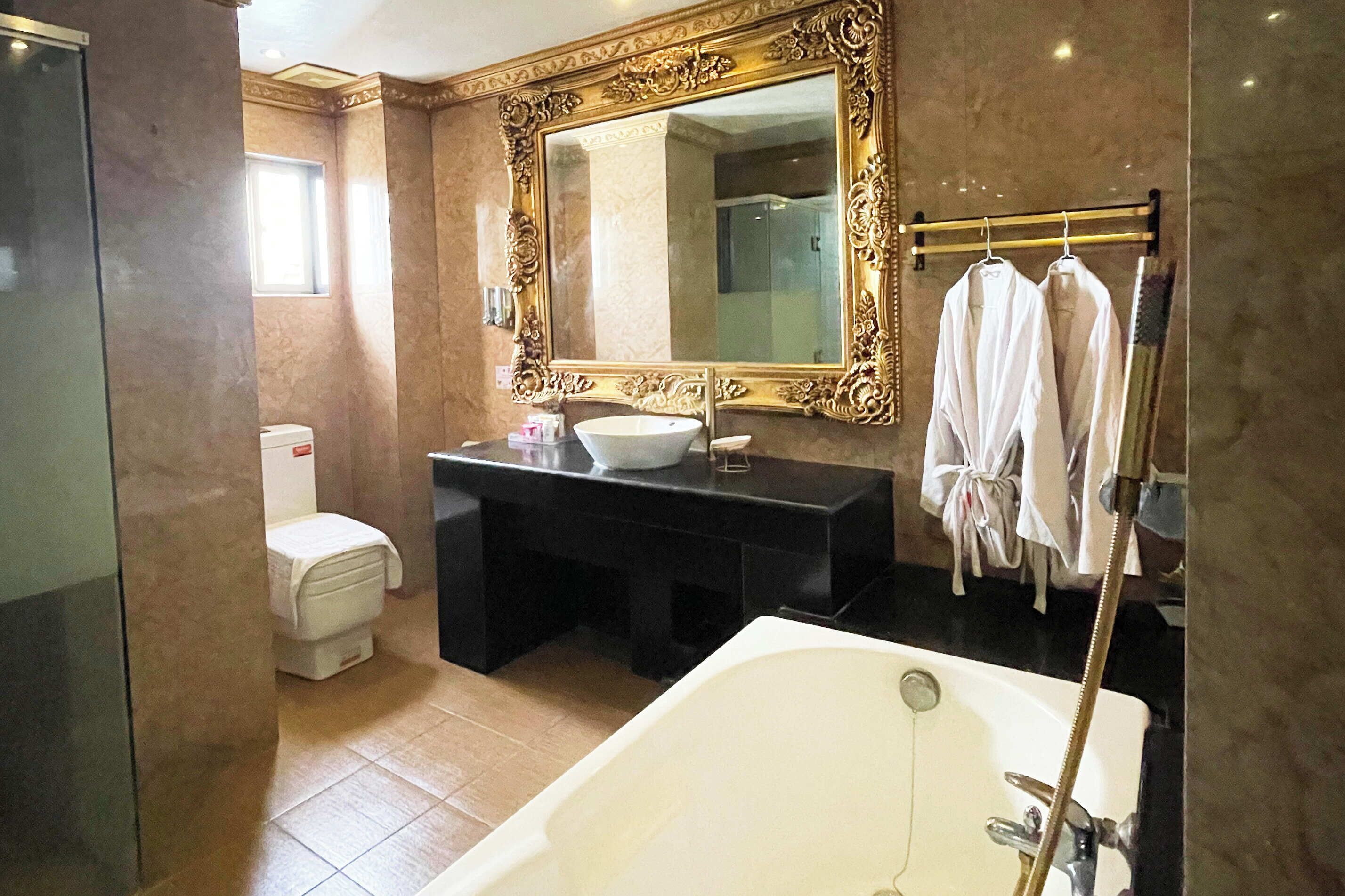 A bathroom with a large mirror, a bathtub, a toilet, and a sink.