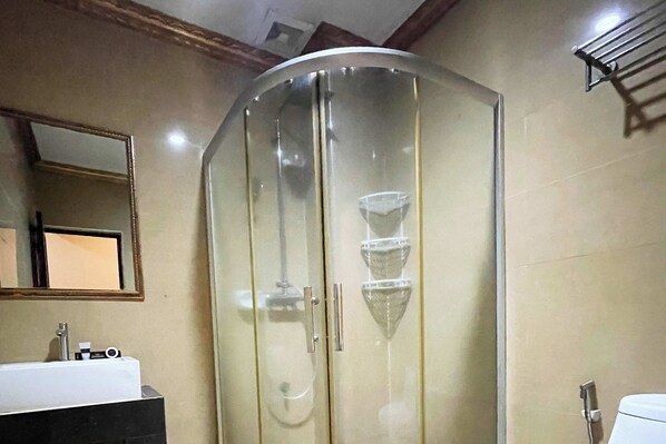 A bathroom with a glass-enclosed shower, a sink, and a mirror on the wall.
