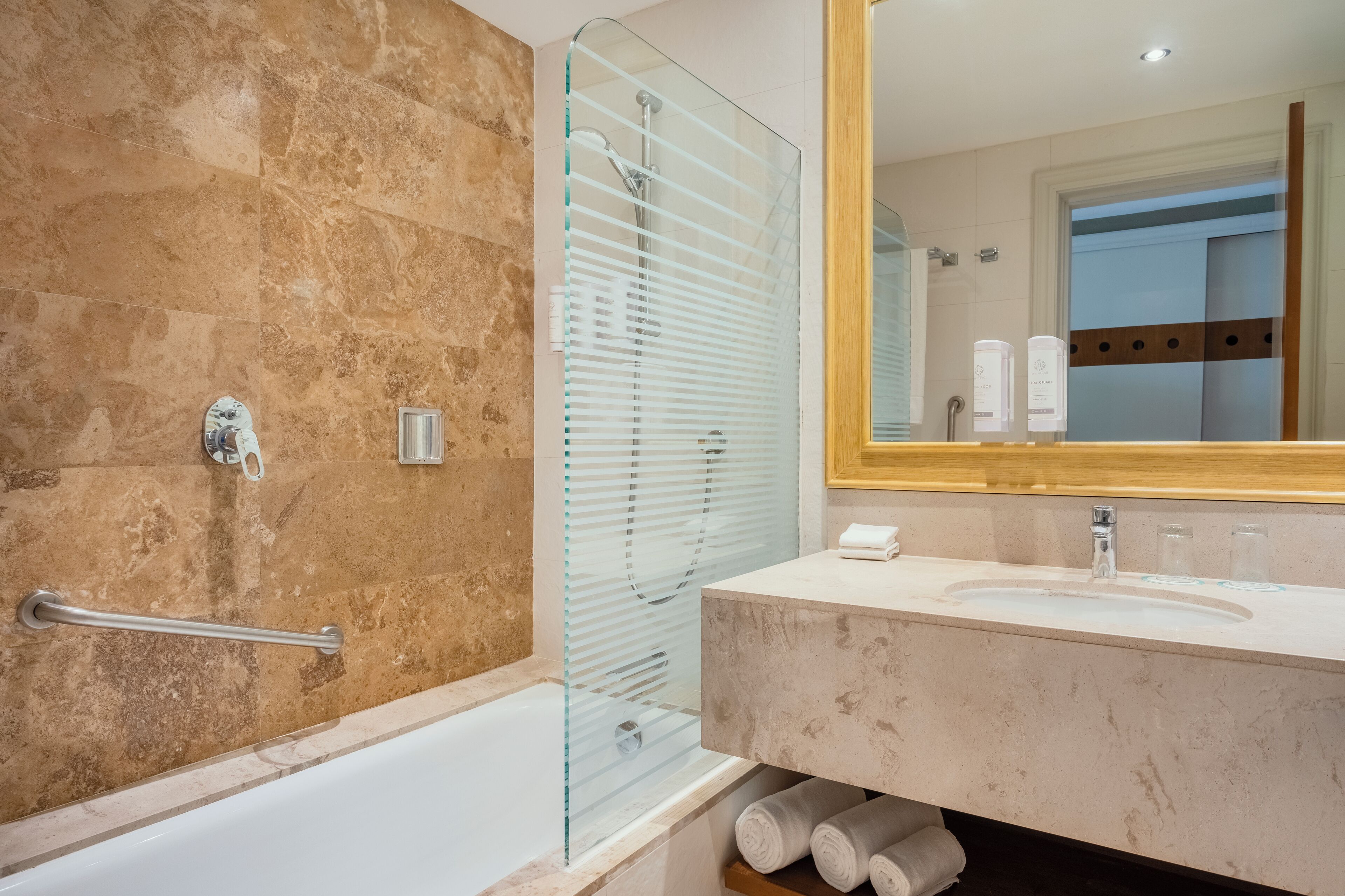 A modern bathroom with a glass shower enclosure, a marble sink, and a large mirror.