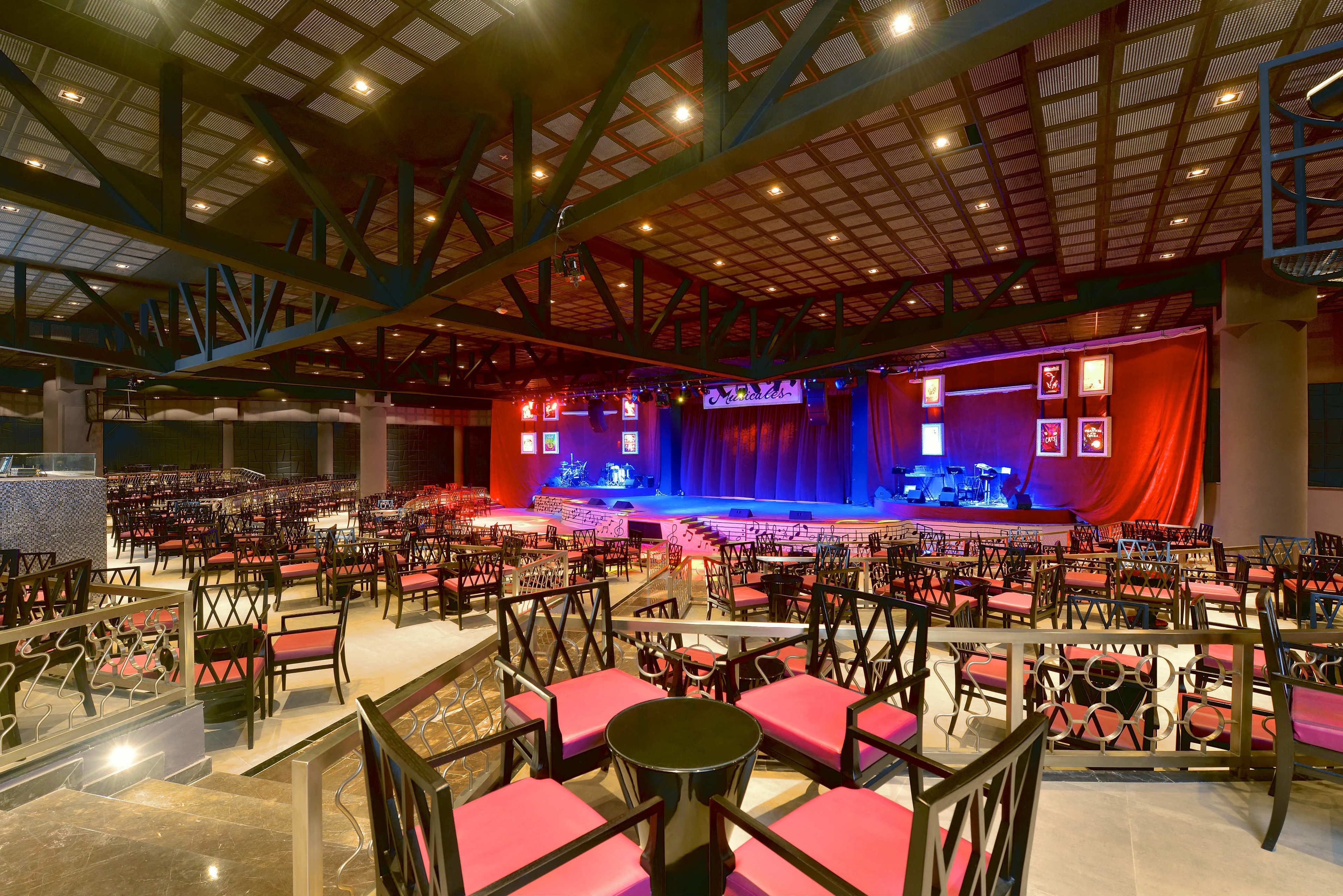 A large indoor auditorium with tiered seating, a stage, and a high ceiling with visible beams.