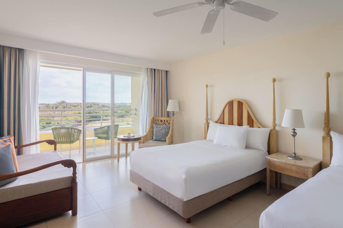 A hotel room with a bed, a chair, a nightstand, and a view of the outdoors.