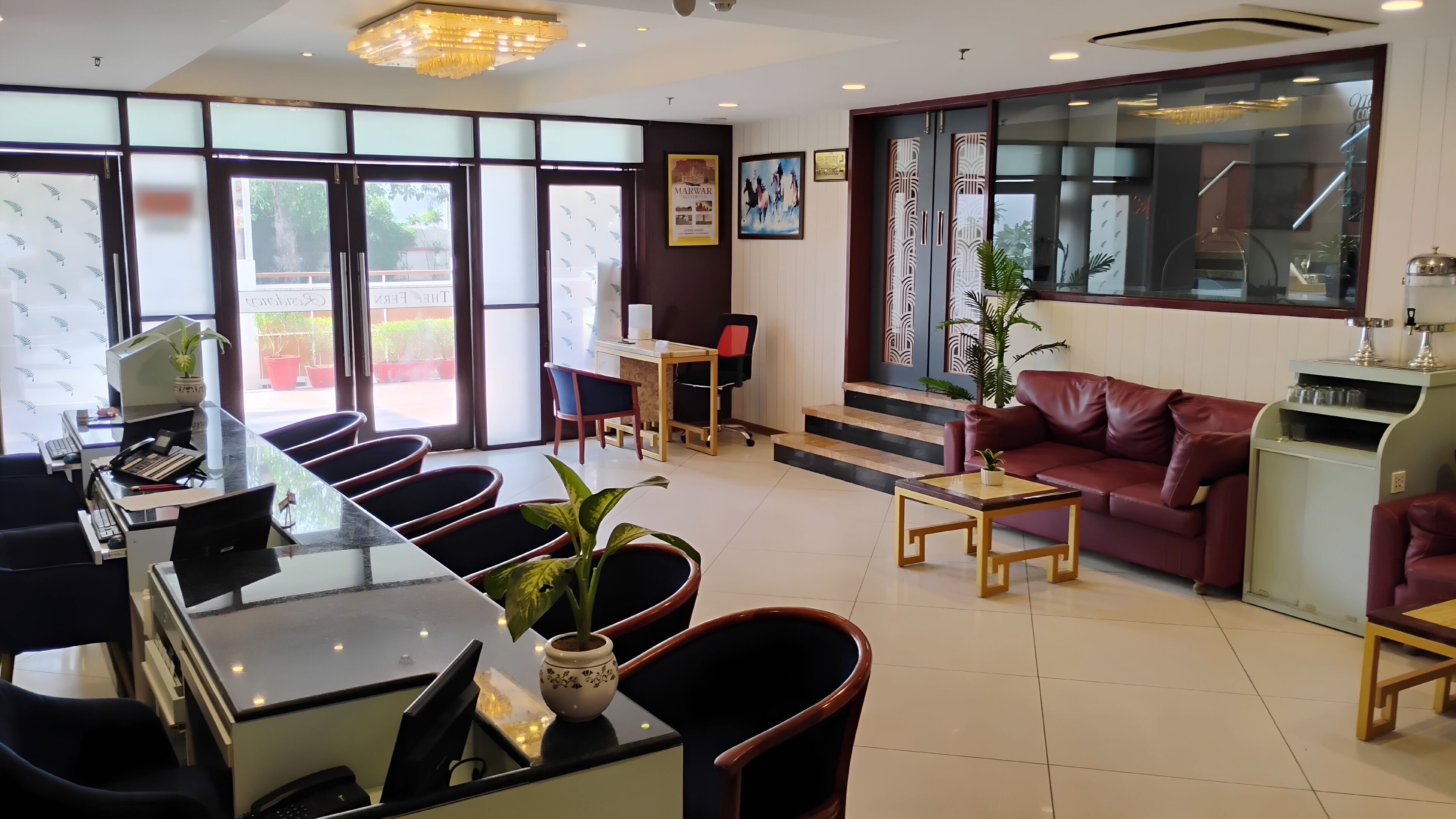 A hotel lobby with a reception desk, seating area, and a staircase leading to an upper floor.
