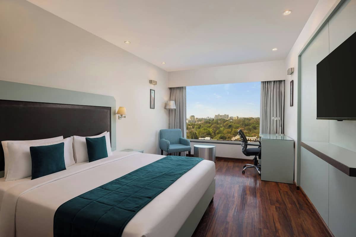 Ein Hotelzimmer mit einem großen Bett, einem Schreibtisch, einem Stuhl und einem Fernseher.