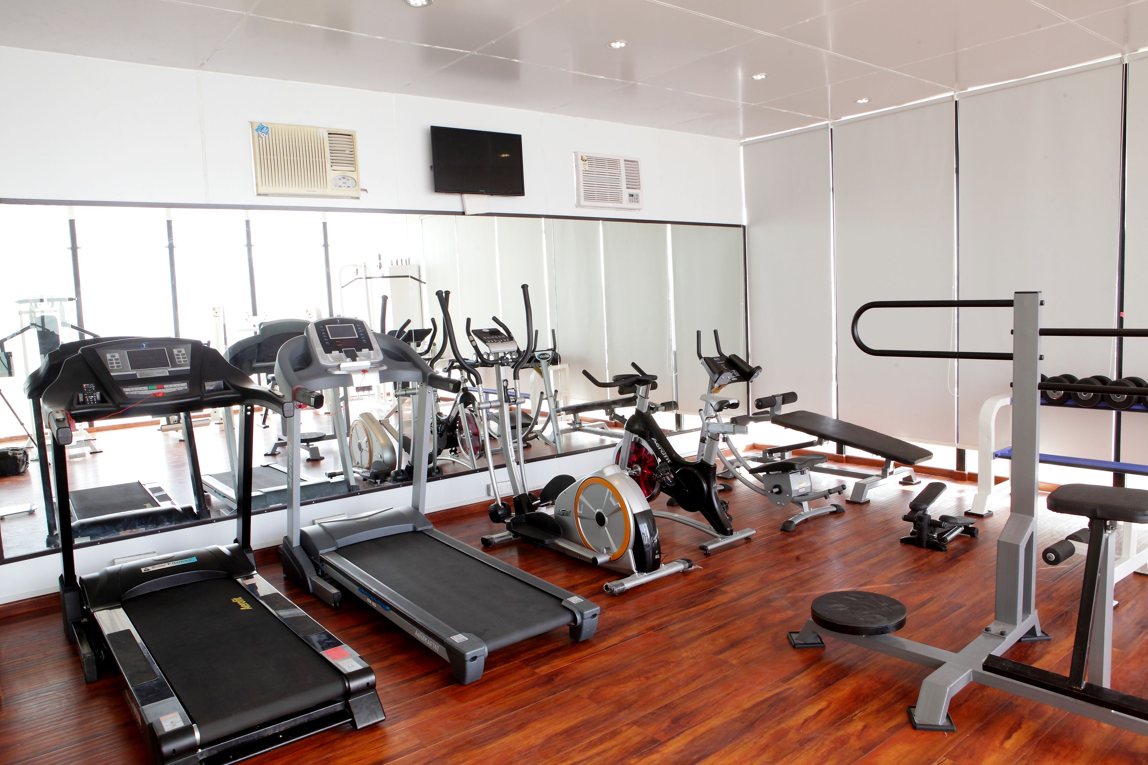 Une salle de sport équipée de tapis de course, de vélos elliptiques et de matériel de musculation.