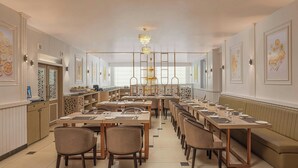 A restaurant with multiple dining tables, chairs, and a chandelier.