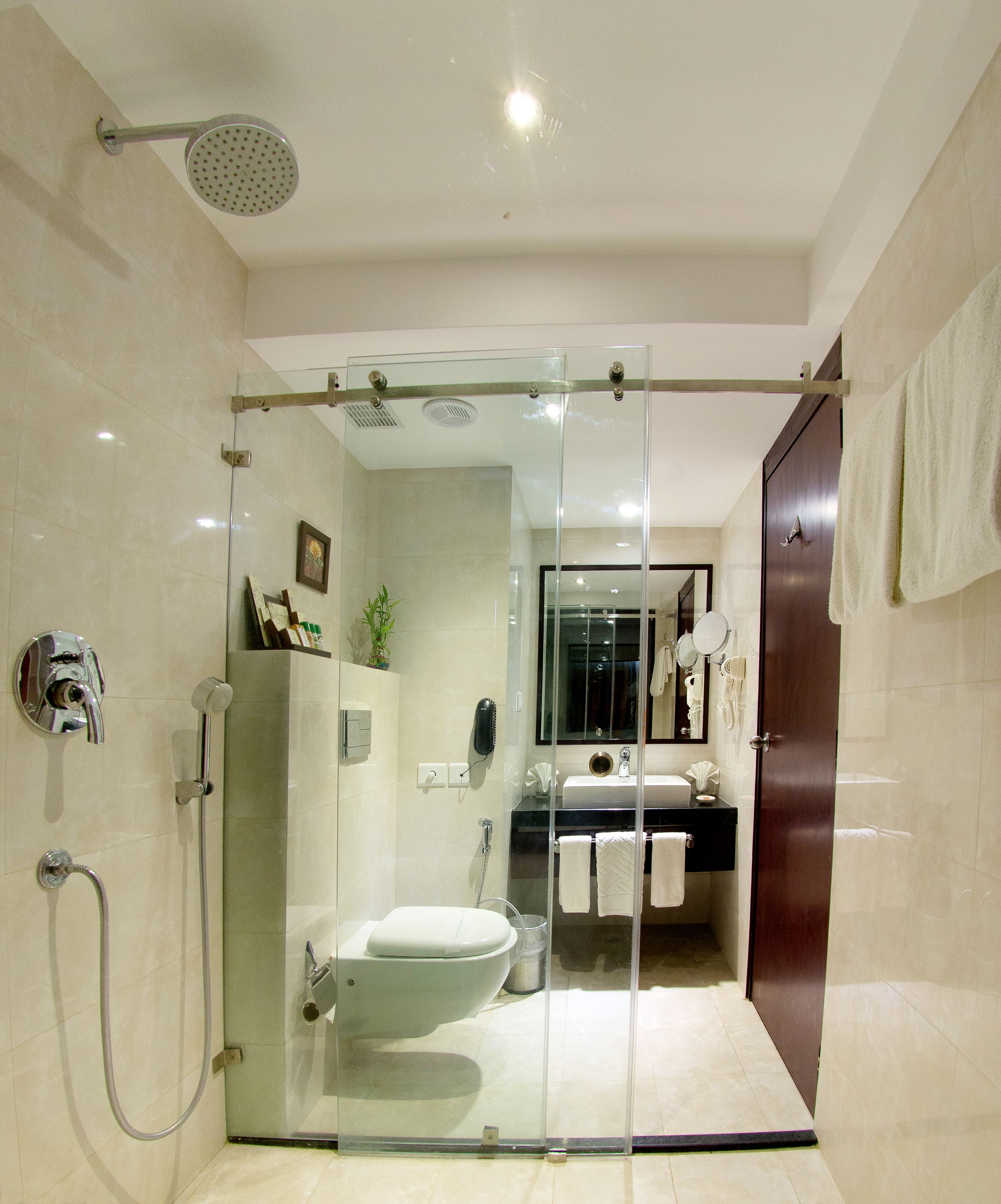 Un baño moderno con ducha de vidrio, inodoro y lavamanos con espejo.