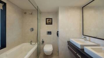 Un baño moderno con ducha de vidrio, inodoro y dos lavamanos con un espejo grande colgando arriba.
