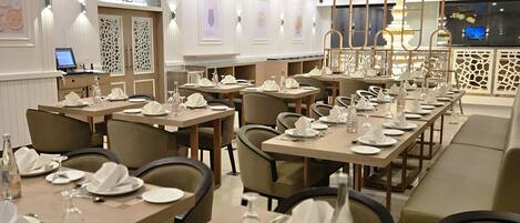 Un restaurante con varias mesas dispuestas para comer, con una decoración interior moderna que incluye iluminación colgante y paneles decorativos en las paredes.