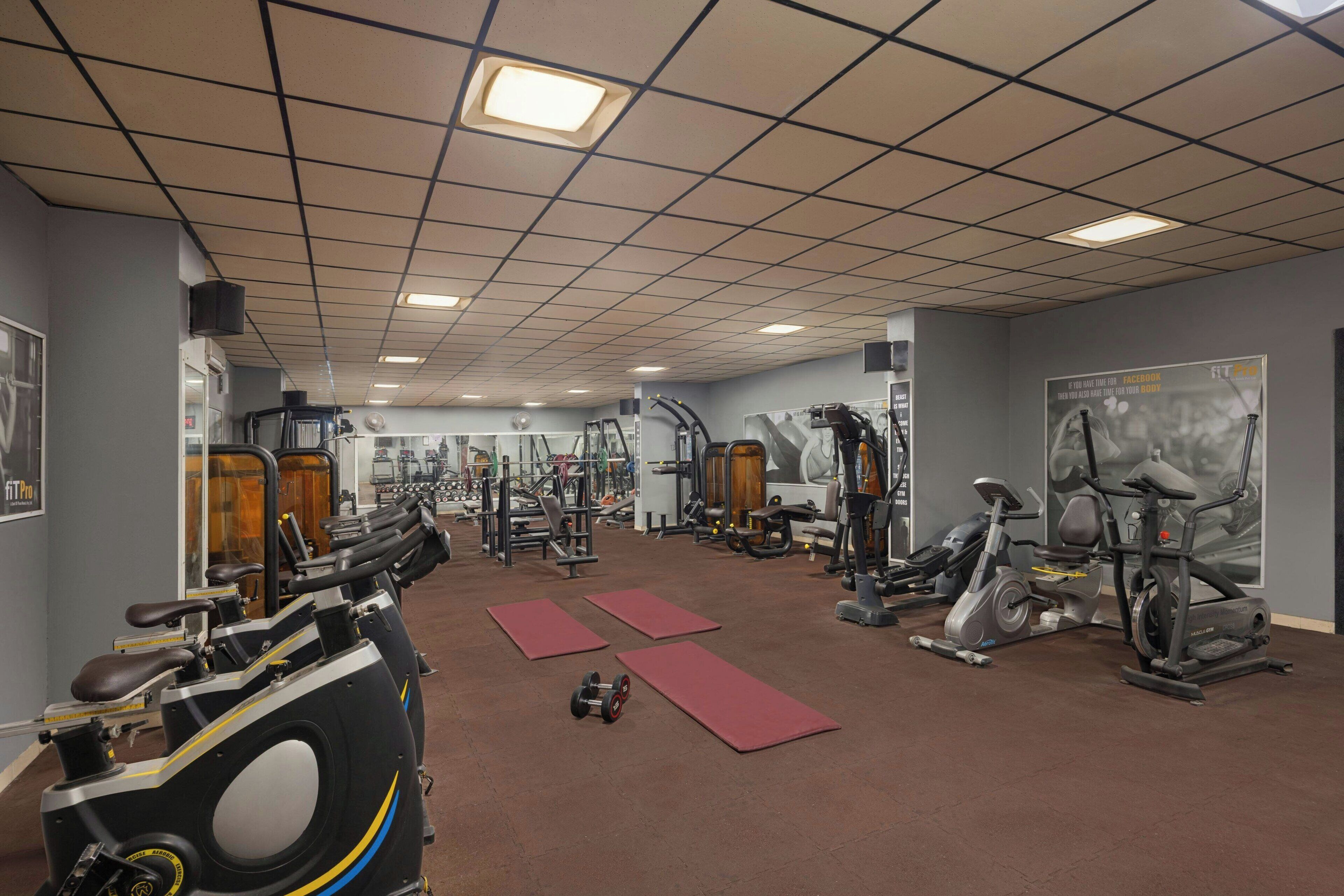 Une salle de sport équipée de divers appareils d’exercice, notamment des tapis de course, des vélos d’appartement et des appareils de musculation.