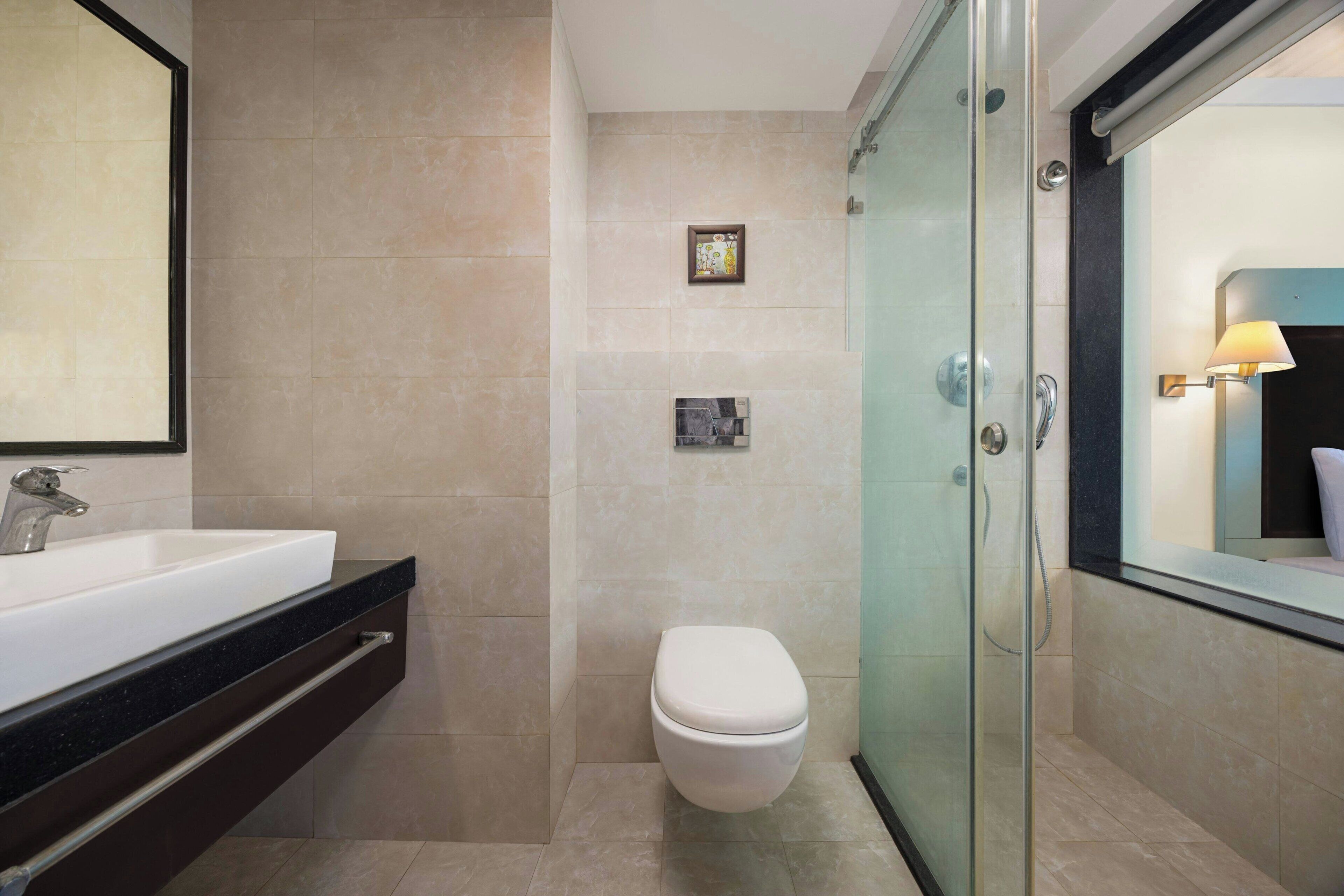 Un baño moderno con ducha de vidrio, lavamanos blanco y retrete.