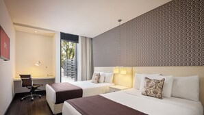 A hotel room with two beds, a desk, and a window with curtains. - Hotel Exe Bacata 95 (Bogotá)
