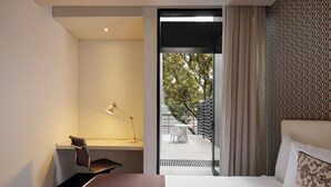 A modern hotel room with a bed, a desk, and a chair. There is a window with curtains, and a view of the outside. - Hotel Exe Bacata 95 (Bogotá)