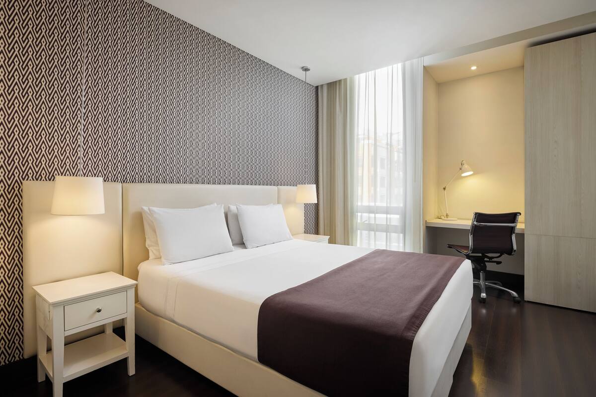 Una habitación de hotel con una cama grande, un escritorio y una silla.