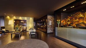 A modern hotel lobby with a reception desk, seating area, and a bar. - Hotel Exe Bacata 95 (Bogotá)