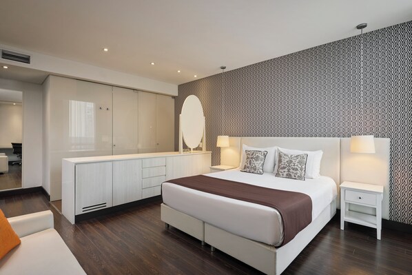 A modern bedroom with a large bed, bedside tables, a wardrobe, and a patterned wall.