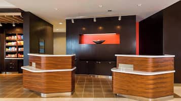 A reception area with two wooden reception desks, a dark wall with a red accent, and a shelf with snacks.