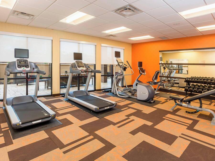 A gym with treadmills, an elliptical, a bench press, and dumbbells.
