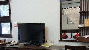 A room with a wooden desk, a television, a chair, a window, and a mirror. - Ping Phu Place (Chiang Mai)