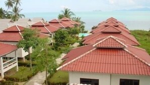 A resort with multiple buildings featuring red-tiled roofs, surrounded by greenery and a view of the ocean. - New Sunrise Village Bang Po Beach (Koh Samui)