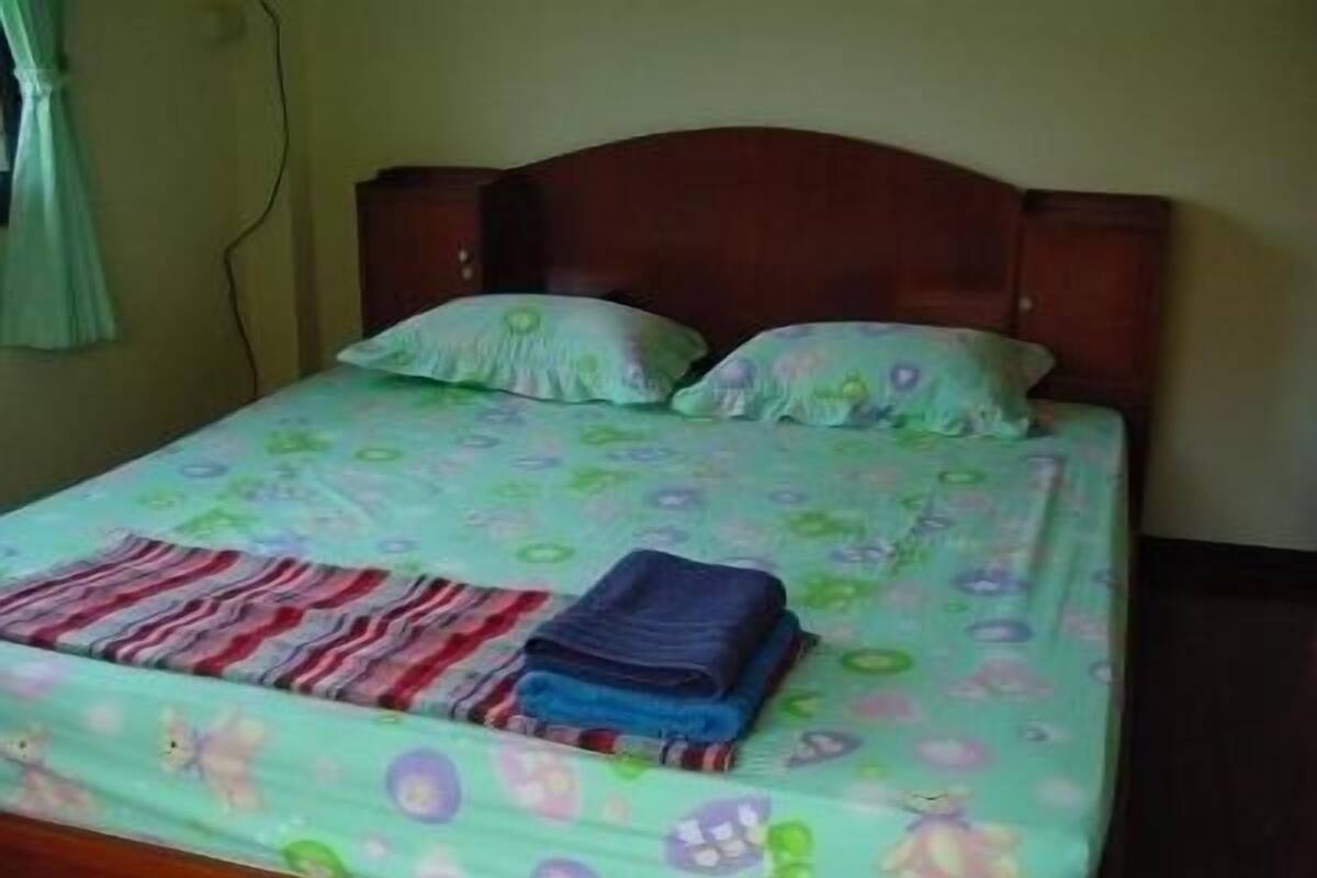 Ein Bett mit blumigem Überwurf, zwei Kissen und gefalteten Decken.