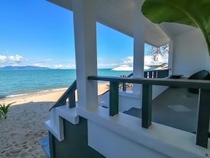 Une vue sur la plage depuis un balcon doté d’une balustrade, avec une plage de sable et l’océan en toile de fond.