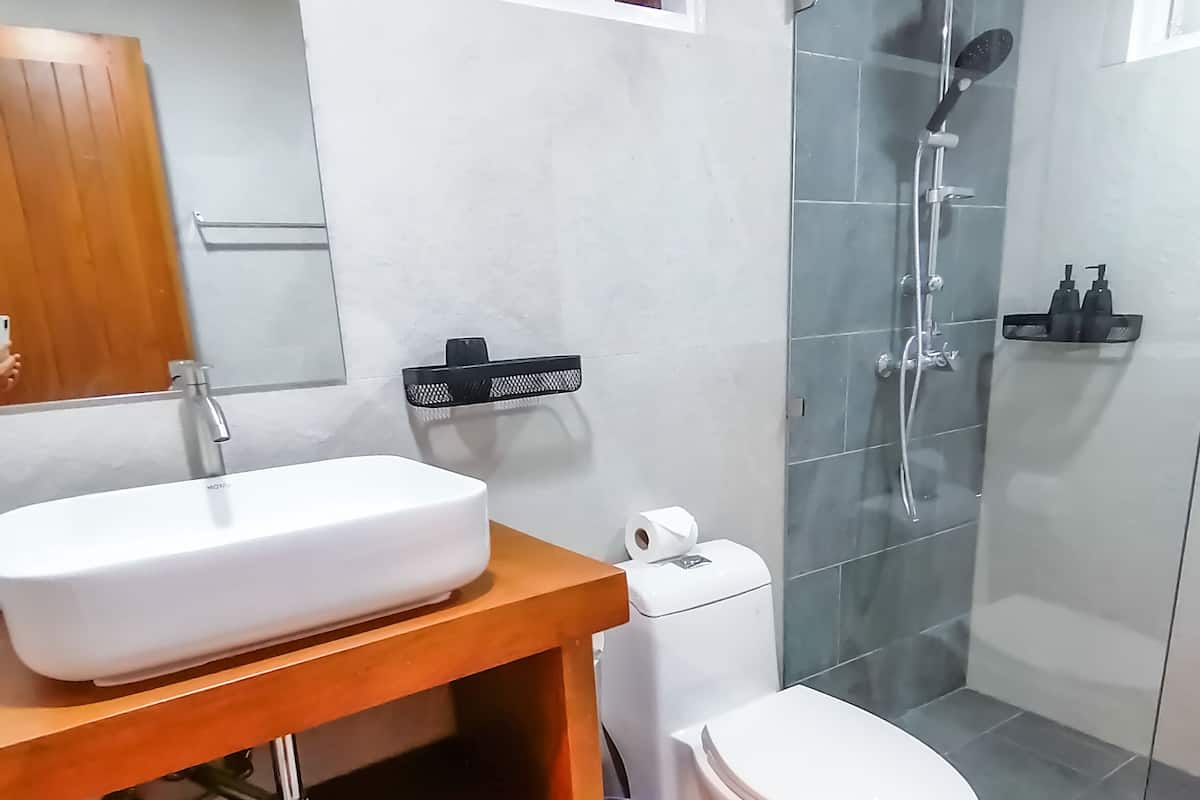 A modern bathroom with a wooden vanity, white sink, and toilet.