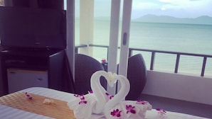 A neatly made bed with a swan-shaped towel arrangement and a single red flower on a striped bedspread. - The Cosy Beach Resort (Koh Samui)