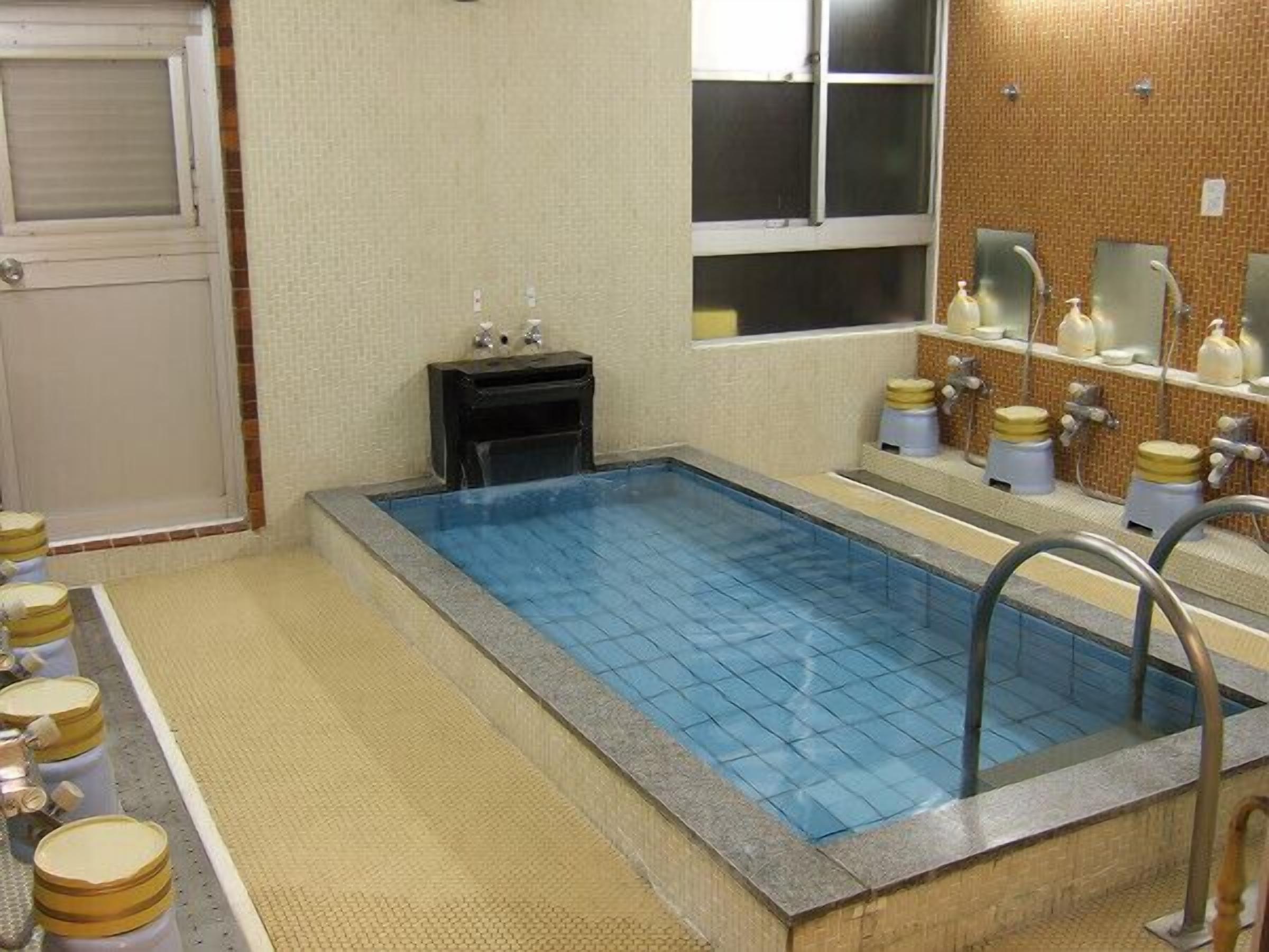 A small indoor pool with a tiled floor and a window above it.
