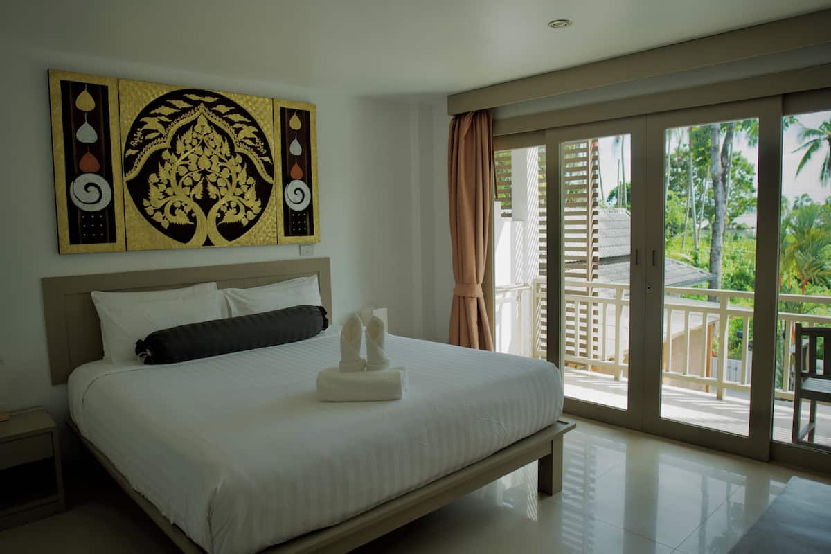 A hotel room with a large bed, a view of the outdoors, and a decorative wall piece.