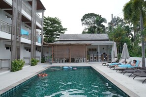 A swimming pool with lounge chairs and a covered seating area. - Ampha Place Hotel (Koh Samui)