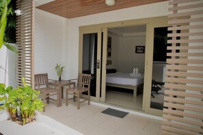 A room with a bed, a desk, and a chair. There is a door leading to another room. - Ampha Place Hotel (Koh Samui)