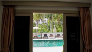An open door leading to a pool area with lounge chairs and umbrellas. - Ampha Place Hotel (Koh Samui)