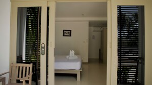 A hotel room with a bed, a chair, and a door leading to another room. - Ampha Place Hotel (Koh Samui)