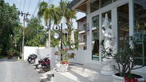 A building with a white statue, potted plants, and parked motorcycles. - Ampha Place Hotel (Koh Samui)