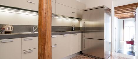 A modern kitchen with a stainless steel refrigerator, white cabinets, and a granite countertop.