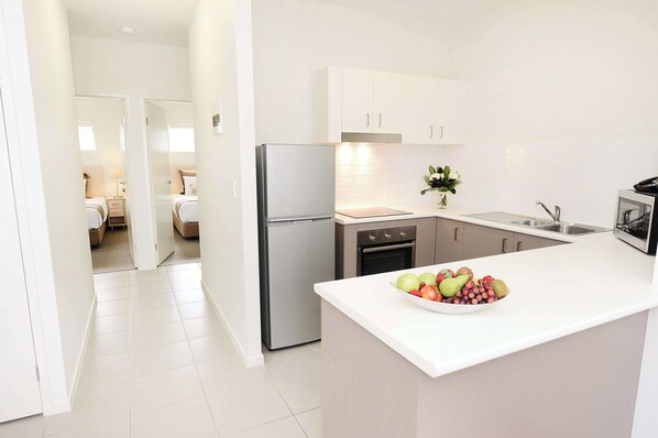 A modern kitchen with white cabinets, a stainless steel refrigerator, and a fruit bowl on the counter.
