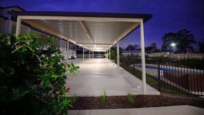 A covered outdoor area with a car parked under a white roof structure. - Oaks Middlemount Suites (Middlemount)