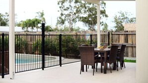 An outdoor patio with wicker furniture and a pool view. - Oaks Middlemount Suites (Middlemount)