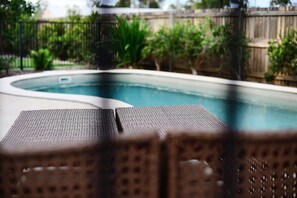 A swimming pool with lounge chairs in the foreground.