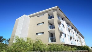 Un edificio de varios pisos con balcones, ventanas amplias y techo plano.