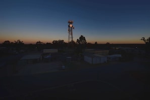A telecommunications tower in a rural setting with sparse buildings and trees. - Oaks Moranbah Suites (Moranbah)