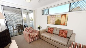 Un salón con sofá, sillón a rayas y televisor sobre un mueble.