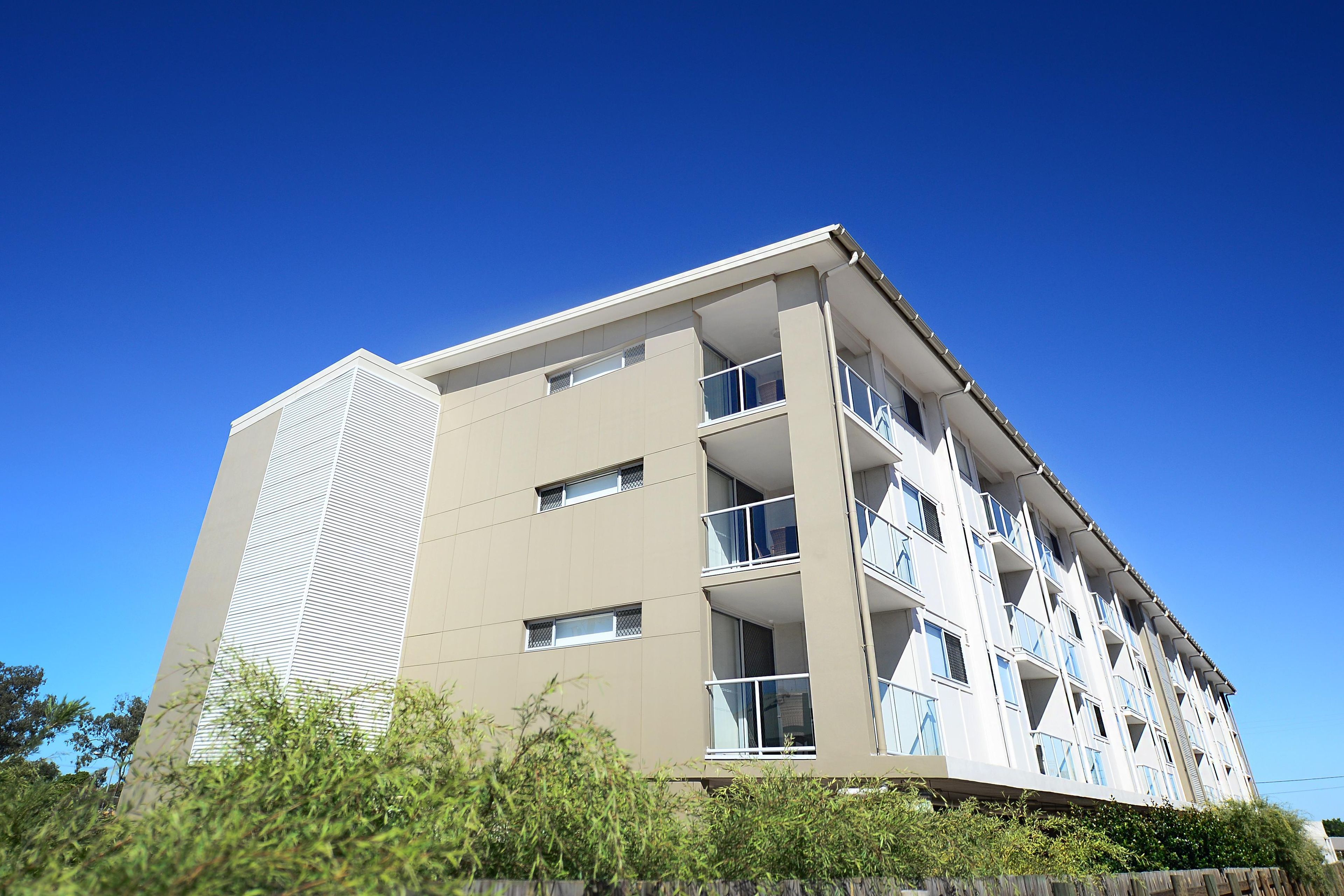 A multi-story building with balconies, large windows, and a flat roof.