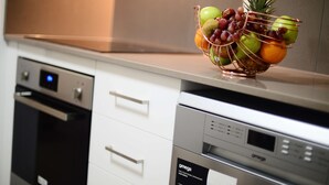 Una cocina con una cesta de frutas sobre la encimera, lavavajillas y estufa.