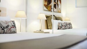 Una habitación de hotel con una cama bien hecha, dos lámparas de noche y un cuadro en la pared.