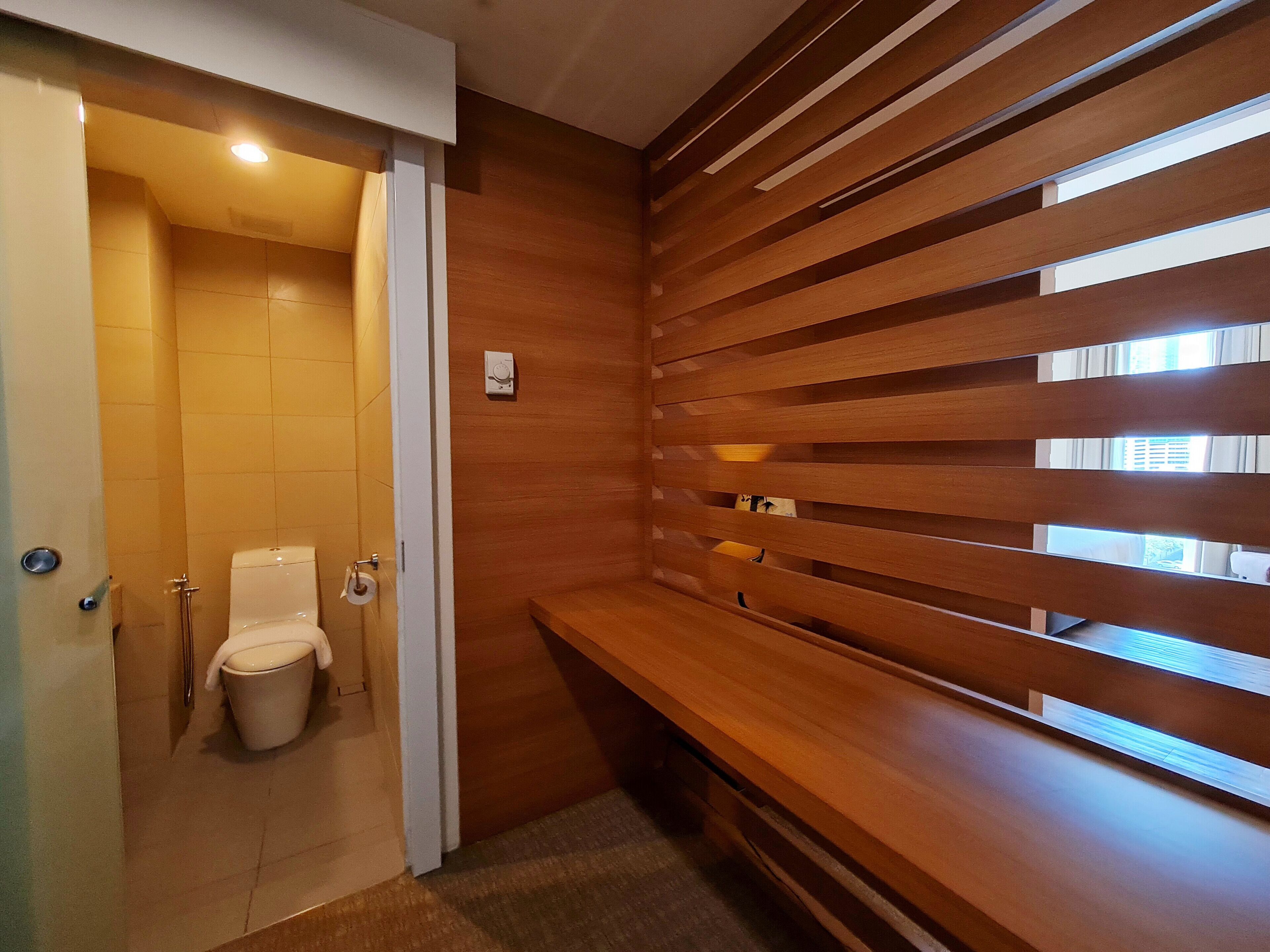 Un baño moderno con inodoro, ducha y pared de listones de madera.