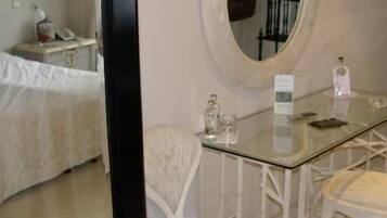 Una habitación de hotel con una cama, una mesita de cristal, una silla, un espejo y un armario.