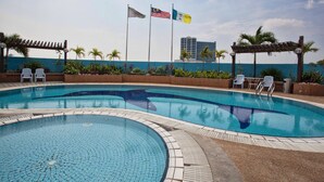 A swimming pool with lounge chairs and flags.