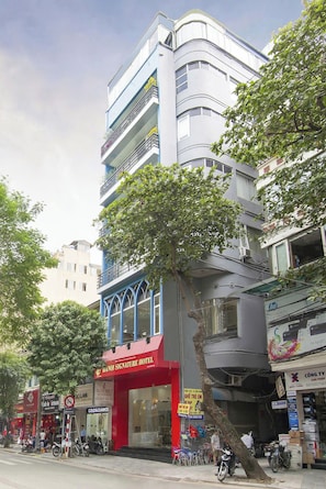 A multi-story building with a red and blue facade, a travel office, and various shops on the ground floor.