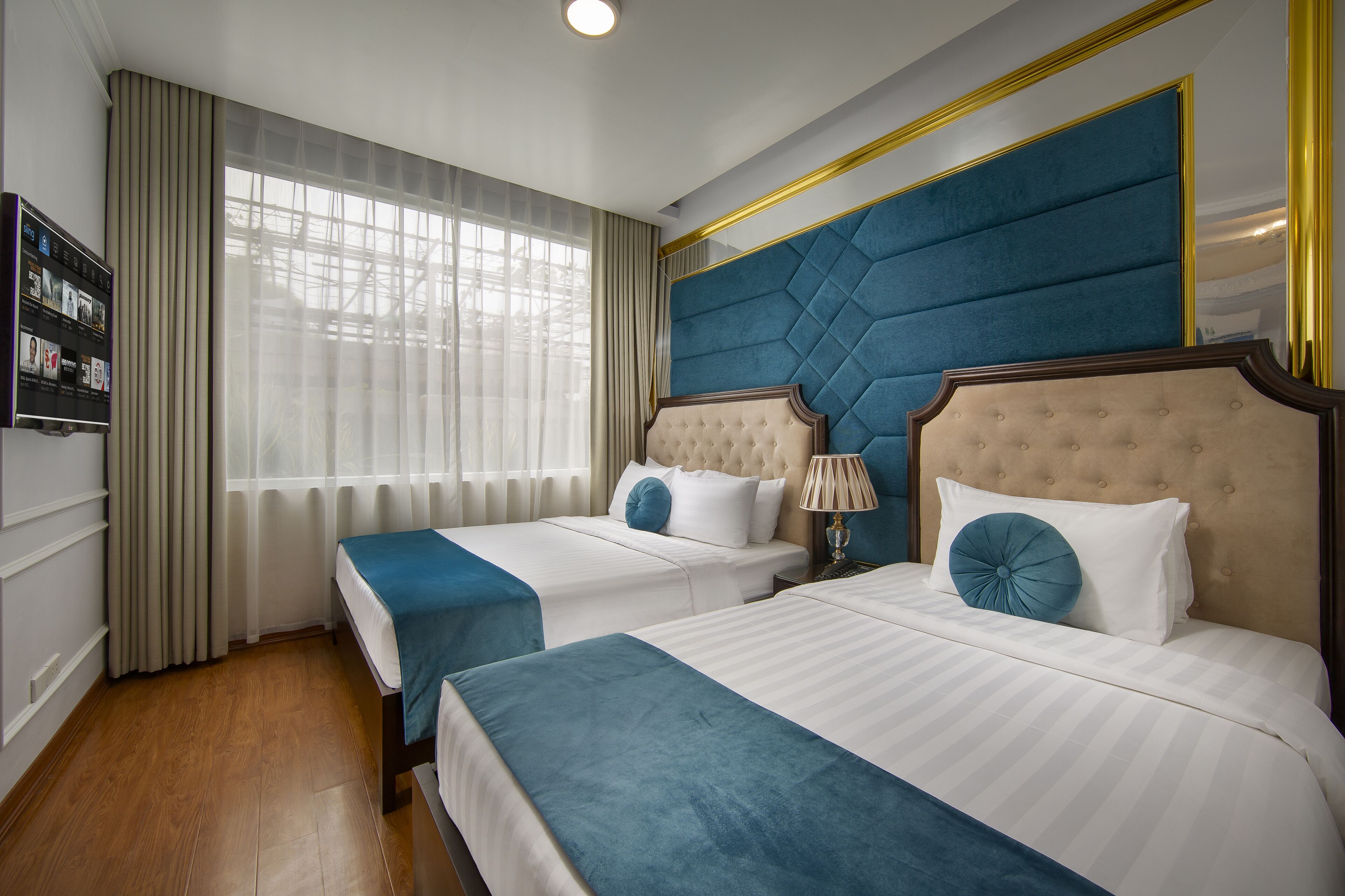 A hotel room with two beds, a TV, and a large window with curtains.